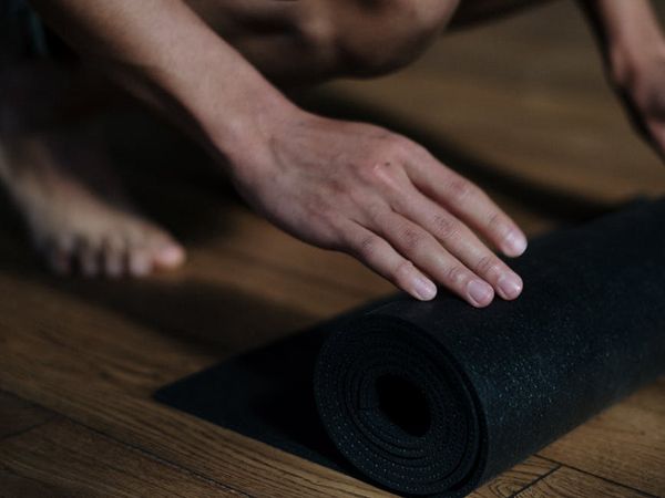 Man practicing mobility exercises on a mat in sunlight
