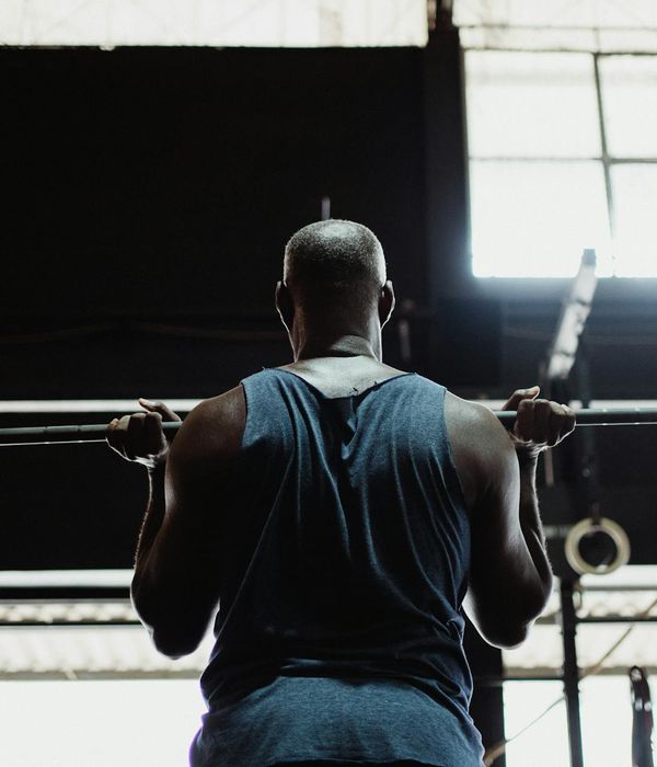 Strong man focused on functional weightlifting exercise in dark gym